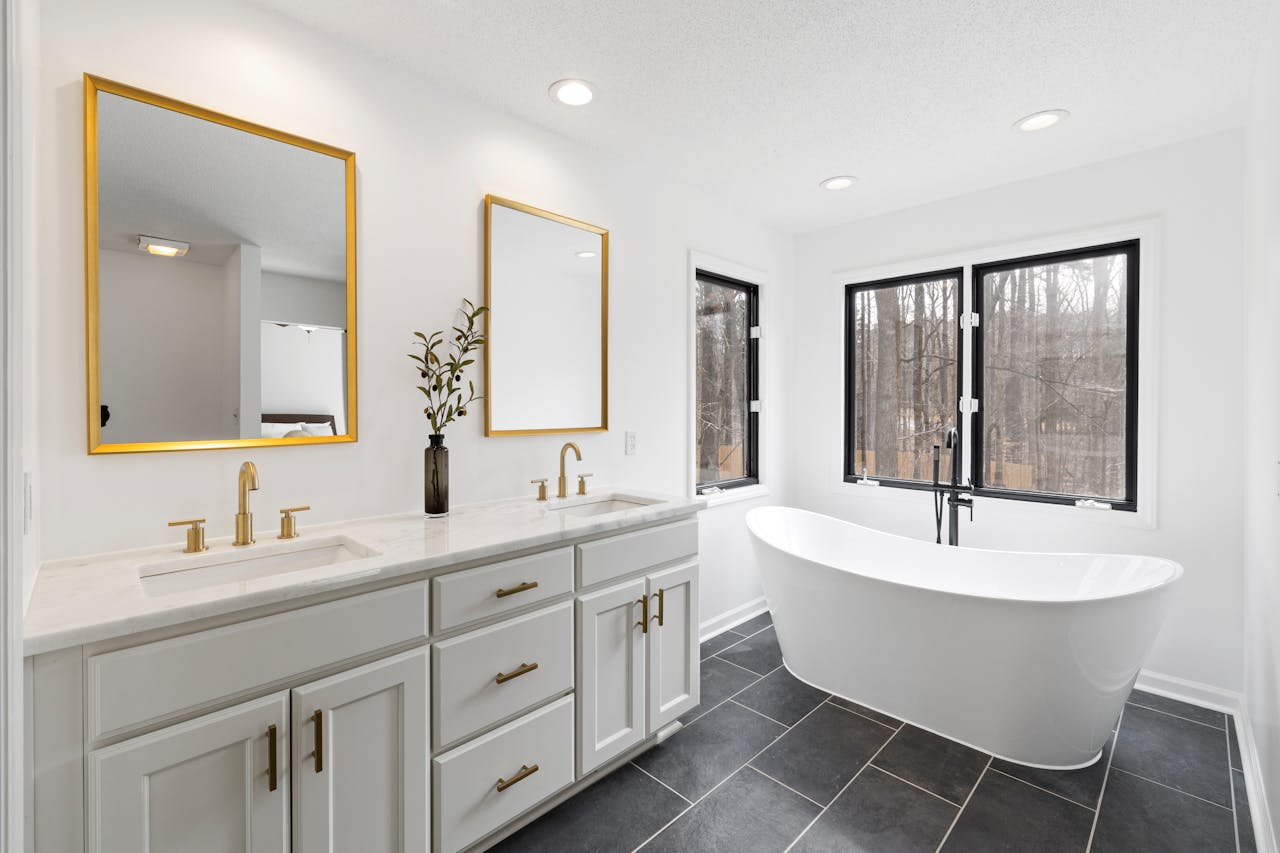 A chic modern bathroom featuring a freestanding tub and dual sinks with gold accents.