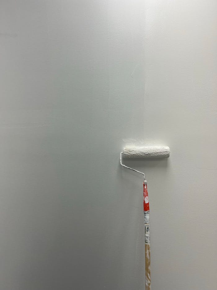 A white wall partially painted with a roller. Minimalist DIY art project.