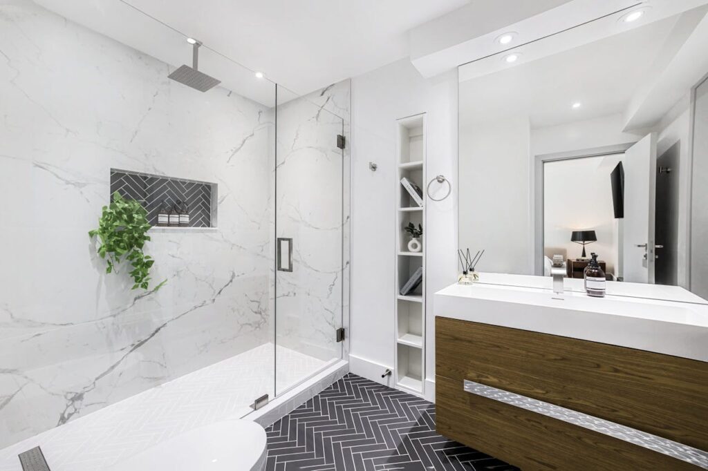 Elegant modern bathroom interior with a glass shower and marble walls.