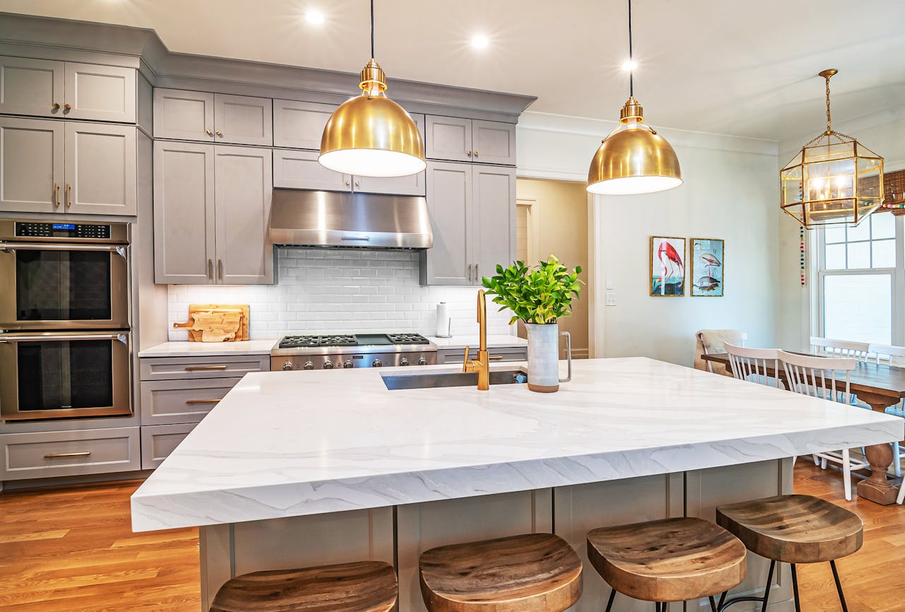 A stylish kitchen featuring a marble island, wood accents, and golden pendant lights.